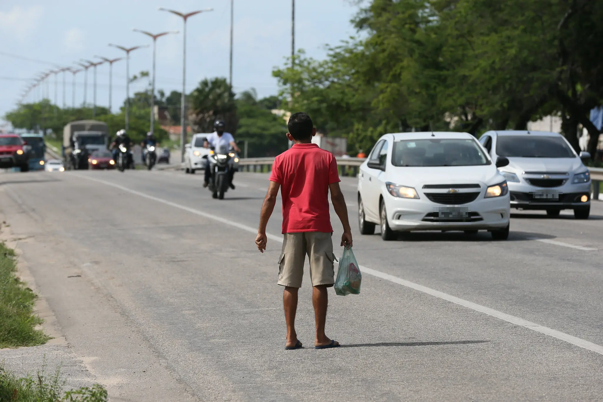 Homem observa trânsito da BR-116 antes de atravessar a via.