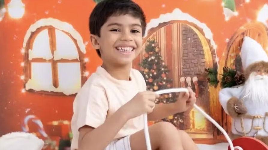 menino Benício posando para foto com decoração natalina.