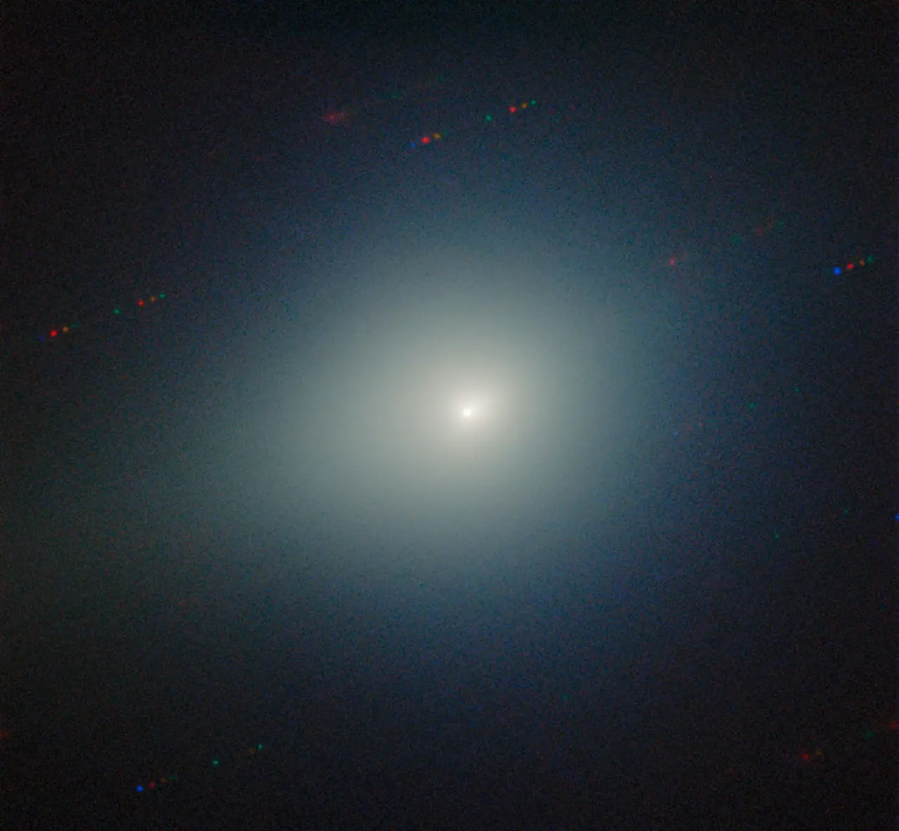 Imagem mostra o cometa interestelar 3I/ATLAS no centro, com um núcleo brilhante envolto por uma nuvem difusa de tonalidade esverdeada.
