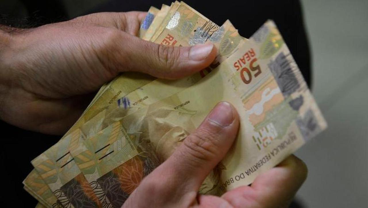 Mão masculina contando dinheiro brasileiro (Real).