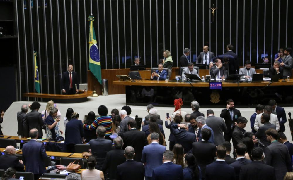 Plenário da Câmara dos Deputados com parlamentares sentados e em pé discursando.