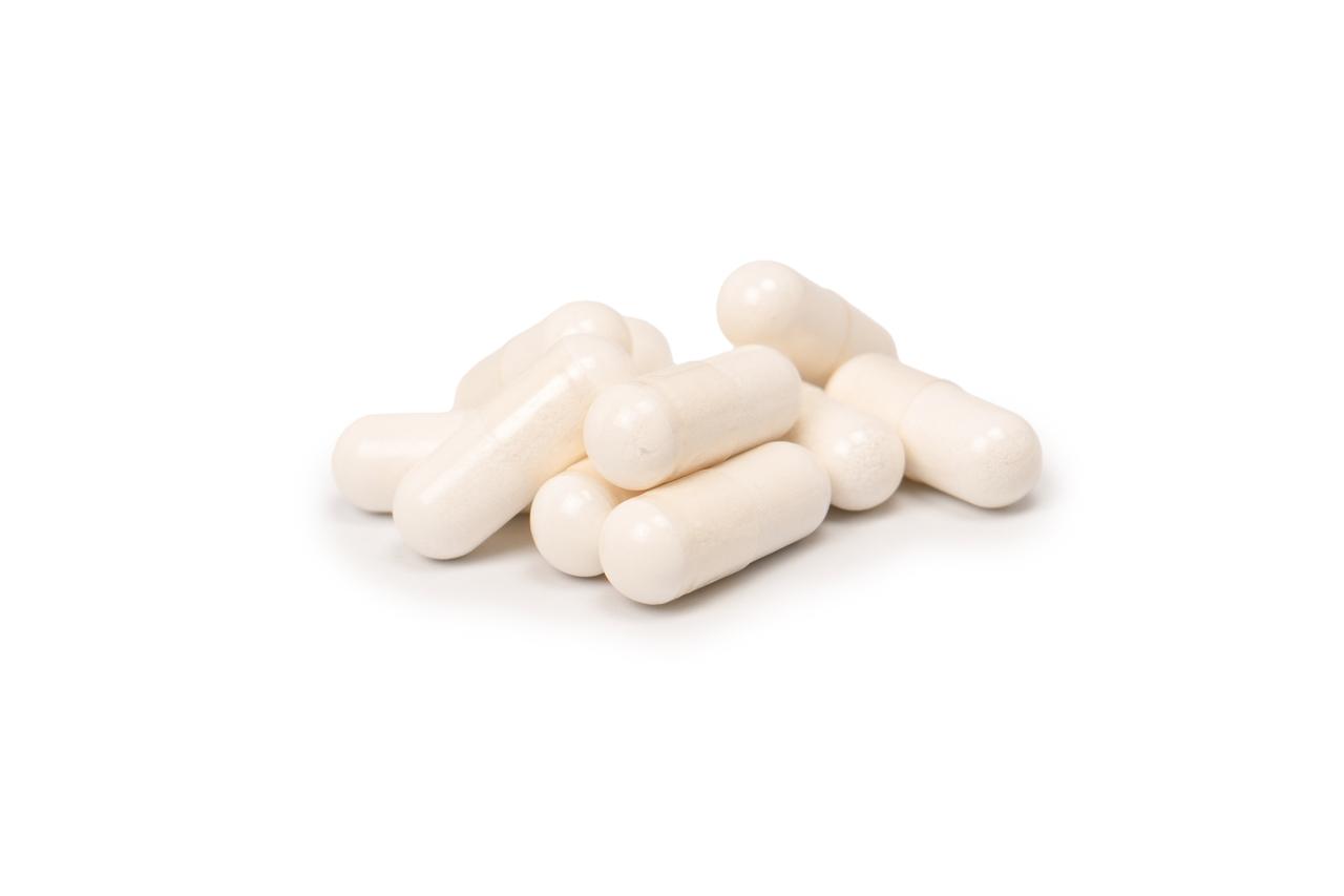 Pílulas brancas revestidas e dispostas em um fundo de cor branca iluminado.
