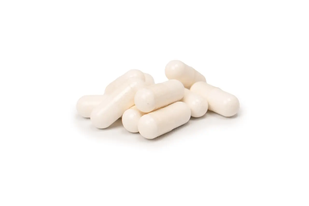 Pílulas brancas revestidas e dispostas em um fundo de cor branca iluminado.