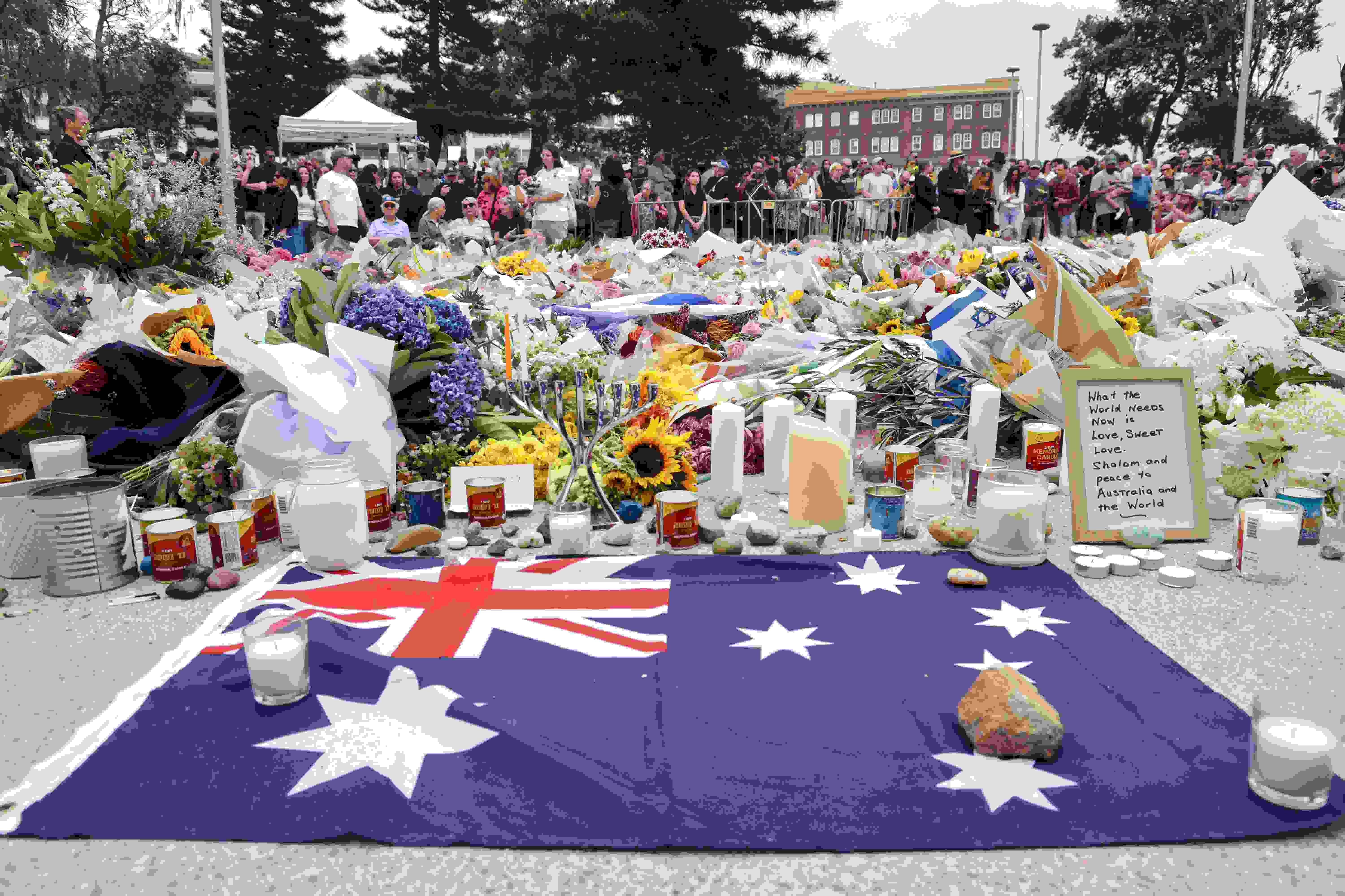 A bandeira da Austrália é vista ao lado de homenagens florais do lado de fora do Bondi Pavilion em Sydney no dia 16 de dezembro de 2025, em homenagem às vítimas do tiroteio na Bondi Beach.