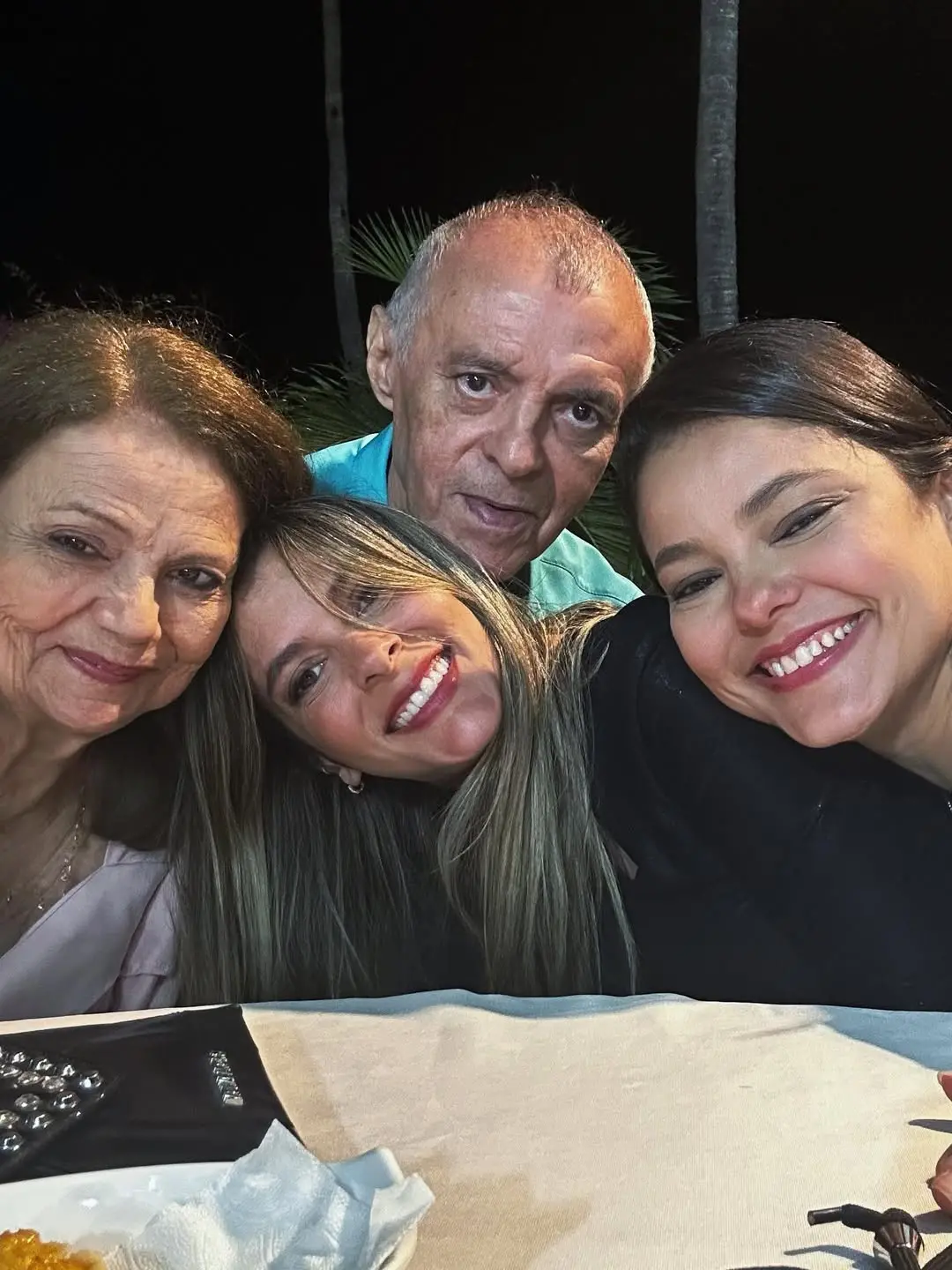 Foto estilo selfie que mostra uma mulher mais velha à esquerda e duas mulheres mais novas ao lado dela; acima, um senhor.