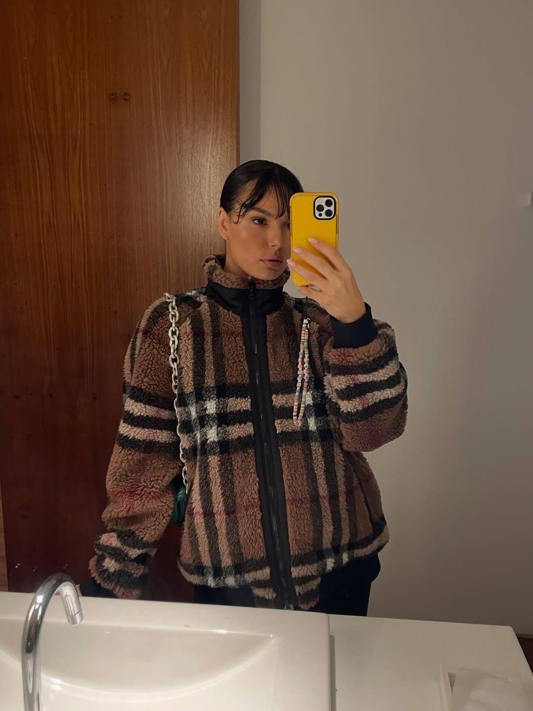 selfie de isis valverde. ela segura um celular amarelo diante do espelho.