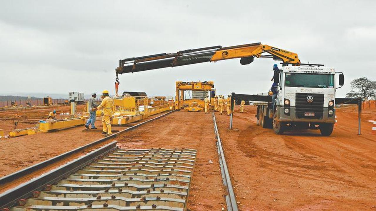 Homens e máquinas trabalhando na construção de trilhos de trem.
