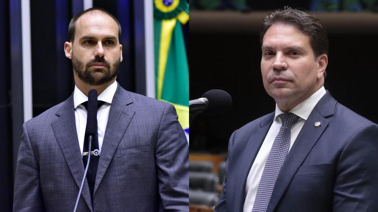 Duas pessoas usando ternos escuros aparecem lado a lado em um ambiente legislativo. Cada uma está posicionada diante de um microfone, com bandeiras e o plenário ao fundo. Ambas vestem camisas sociais claras e gravatas, transmitindo um contexto formal de pronunciamento ou sessão parlamentar.