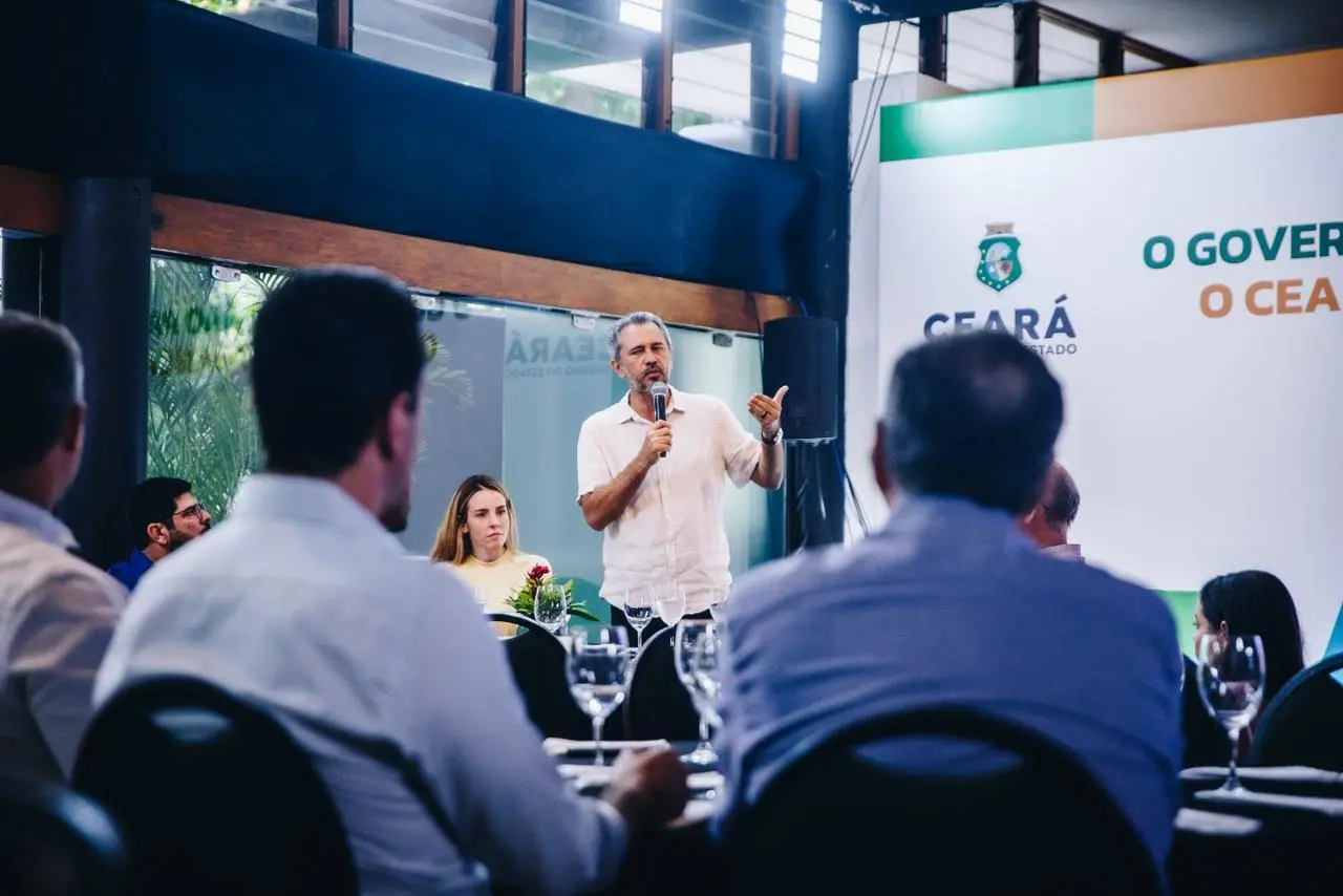 Governador Elmano de Freitas, de pé, discursa para seus secretários. Ao lado dele, a vice-governadora Jade Romero.