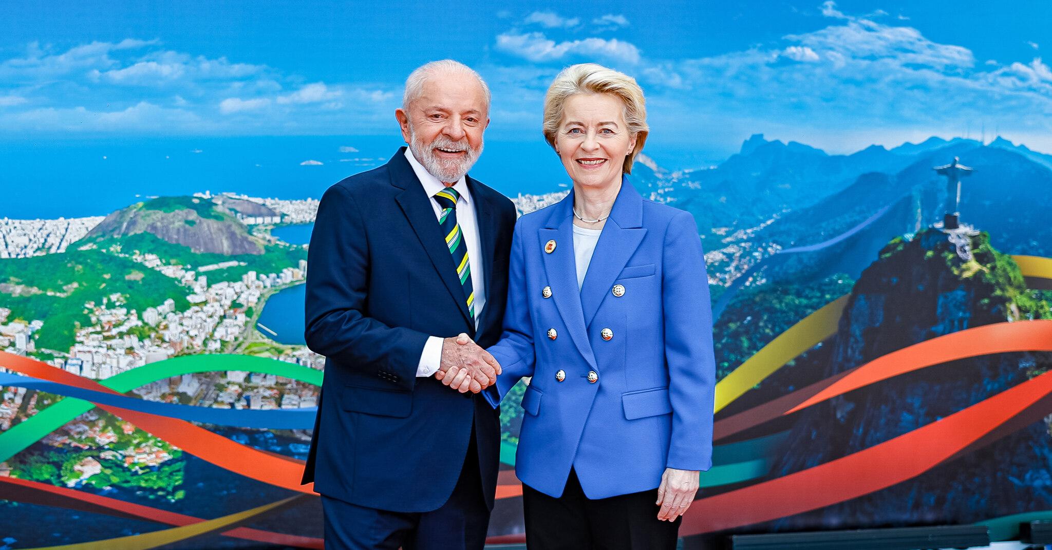 O presidente da República, Luiz Inácio Lula da Silva, e a presidente da Comissão Europeia, Ursula von der Leyen, posam em frente a painel com fotografia de vista do Rio de Janeiro.