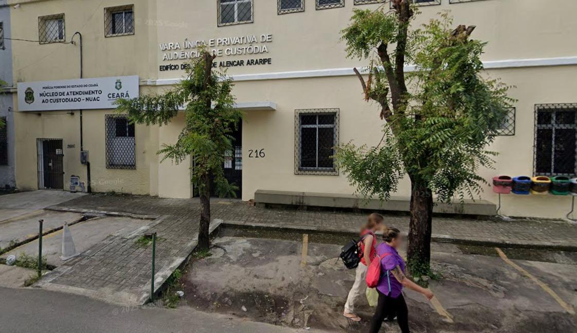 A imagem mostra a fachada da Vara de Audiências de Custódia de Fortaleza, um prédio amarelo com branco, em Fortaleza.