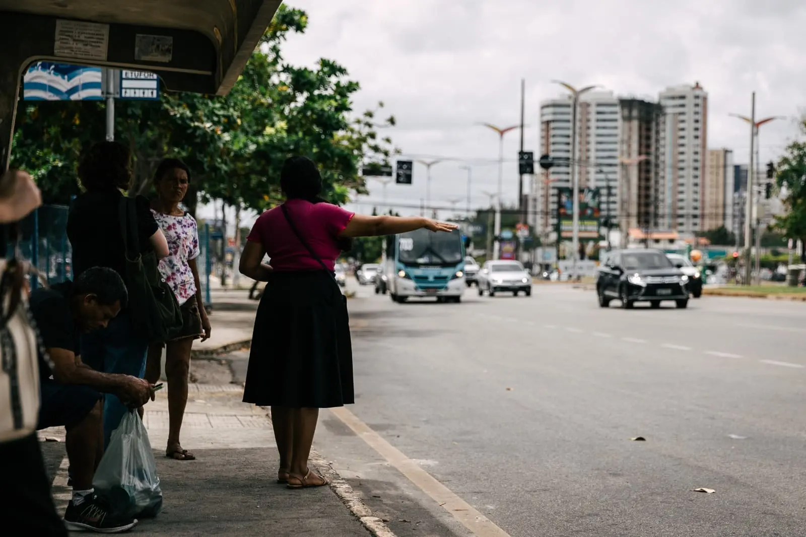 Foto de passageira acenando para que ônibus pare.