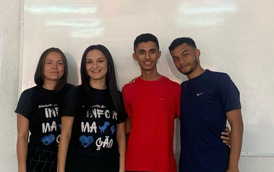 Imagem mostra quatro alunos do IFCE, duas meninas vestindo um uniforme azul marinho e dois meninos, um vestindo camisa vermelha e outro azul marinho.