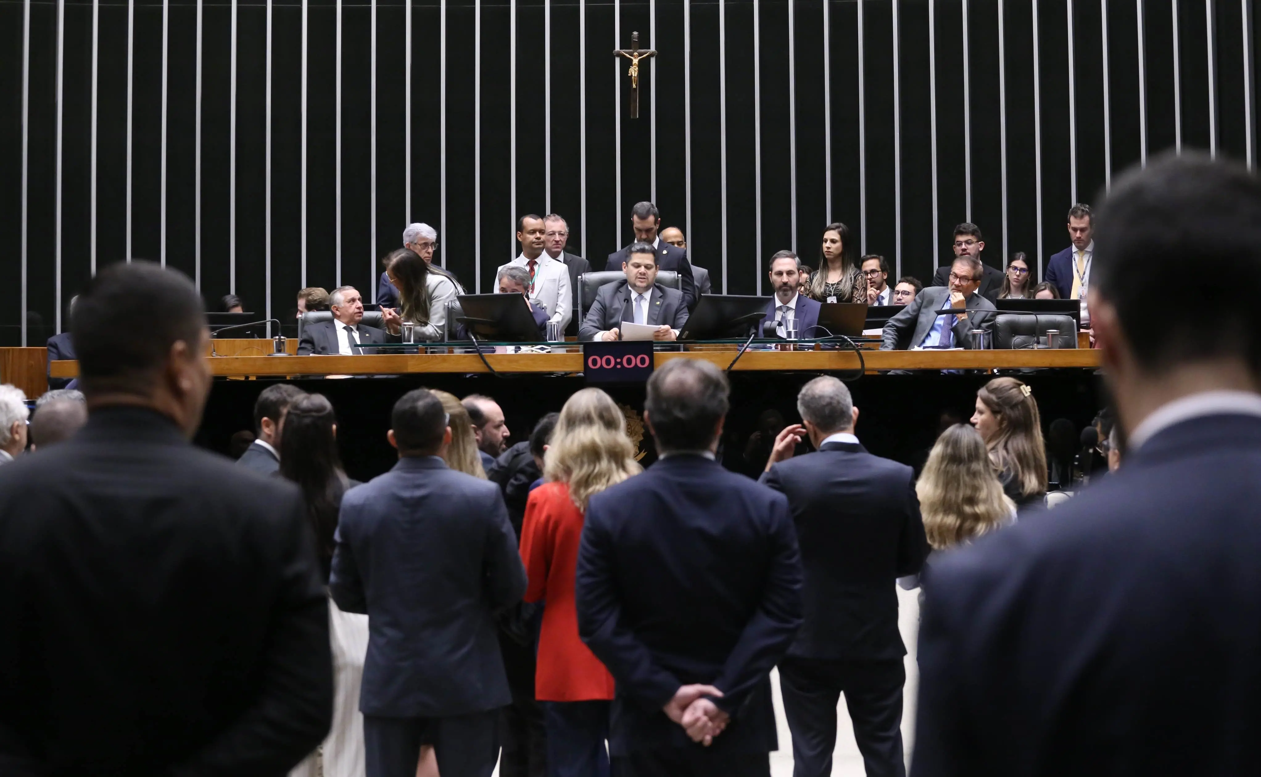 Presidente do Congresso, Davi Alcolumbre, preside a sessão. A Mesa Diretora está composta por deputados e senadores. O plenário está cheio de legisladores em pé.