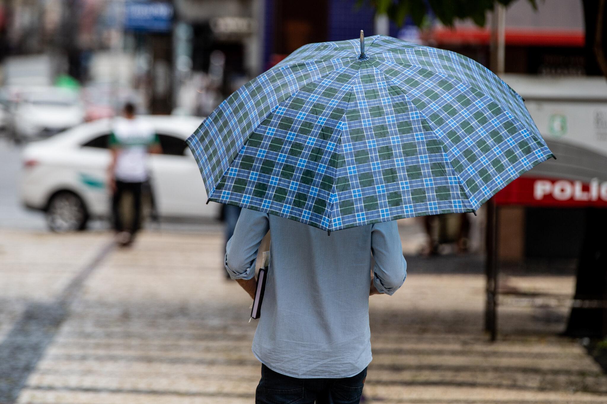 Homem de costas com guarda-chuvas.