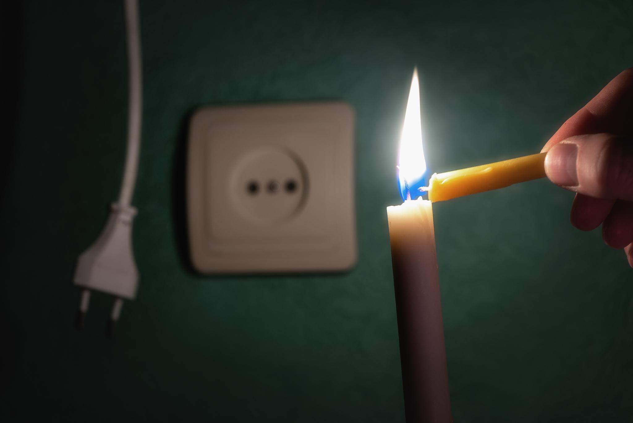 Pessoa acende vela em meio a falta de energia elétrica.