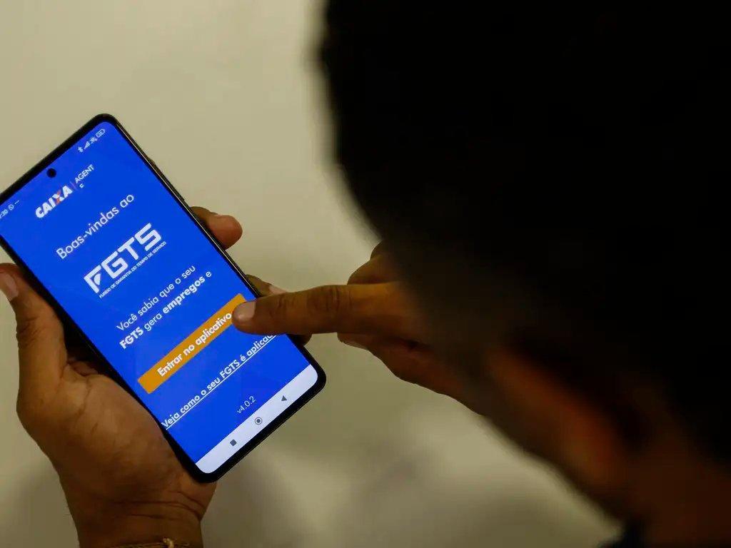 Homem usa celular com o aplicativo do FGTS aberto. Imagem usada em matéria sobre saque-aniversário.