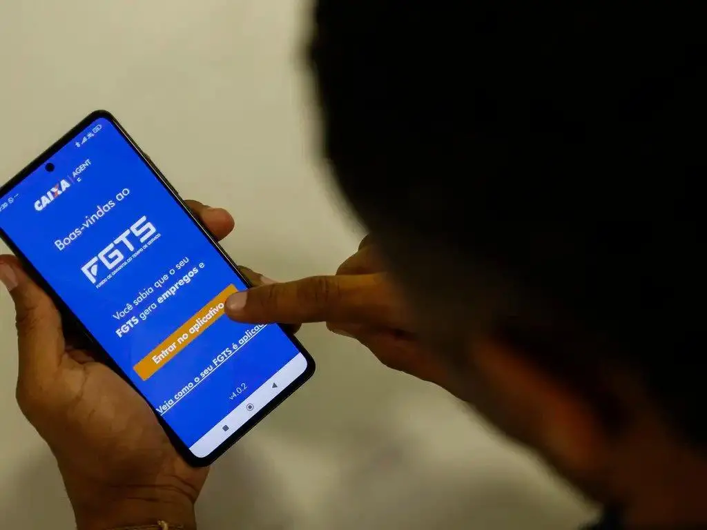 Homem usa celular com o aplicativo do FGTS aberto. Imagem usada em matéria sobre saque-aniversário.