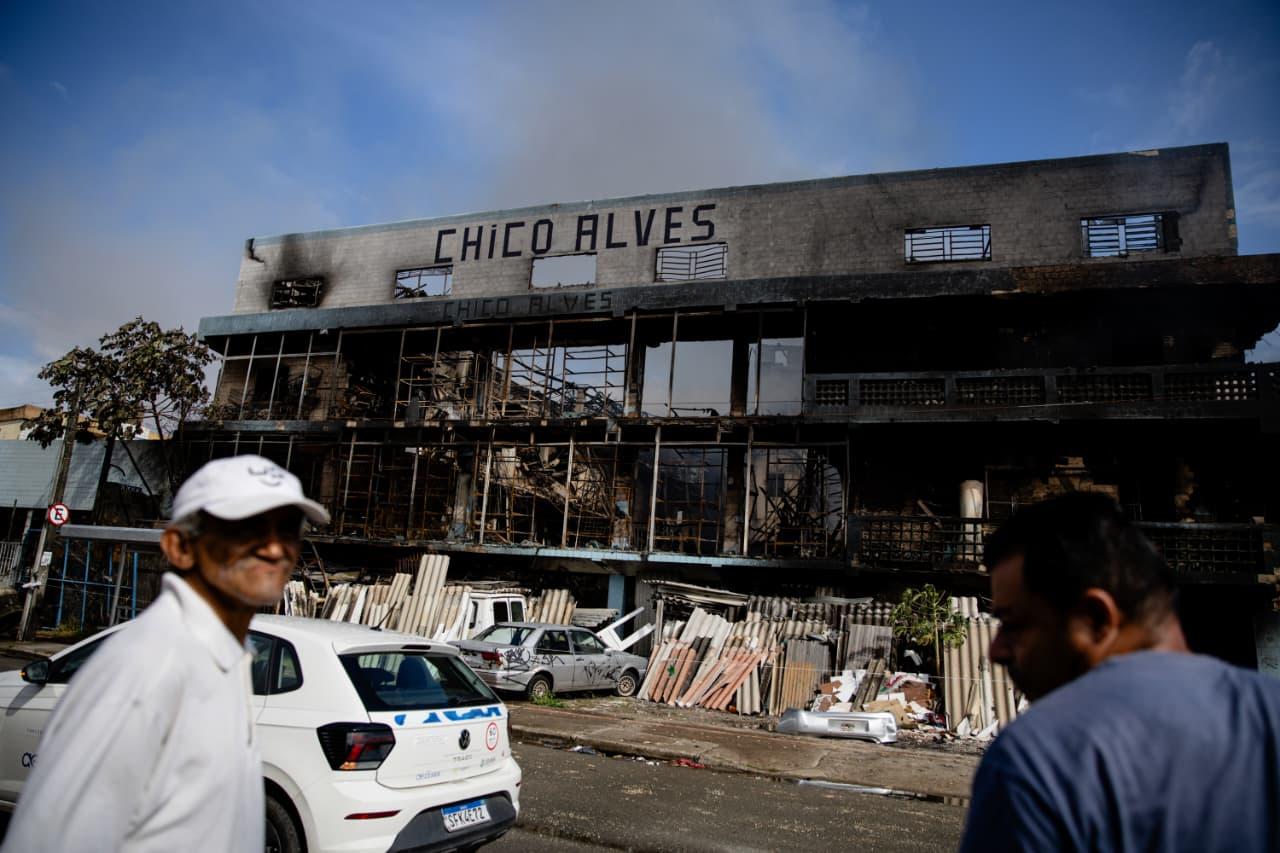 Imagem mostra pedestres observado sucada do chico alves destruída após incêndio em Fortaleza.