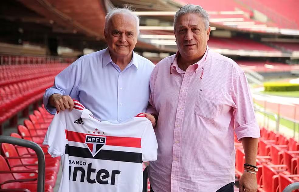 dois homens segurando camisa do SP