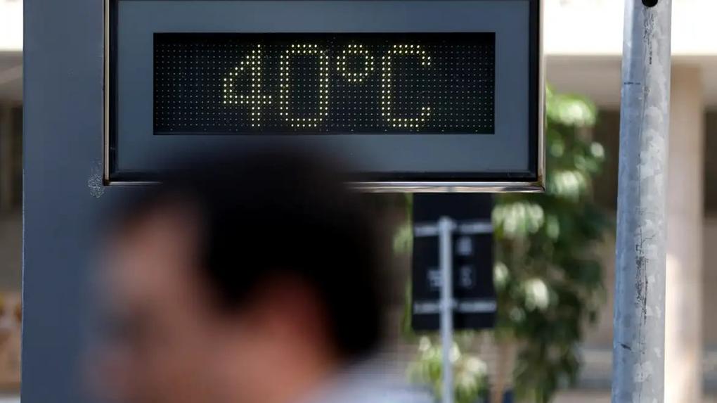 Placa de led com a temperatura de 40 graus. Em primeiro plano, embaçado, uma pessoa passa pela rua.