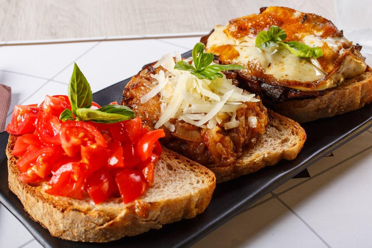 Três torradas enfileiradas. Da esquerda para a direita, os recheios são de tomate seco, queijo ralado e carne com queijo derretido.