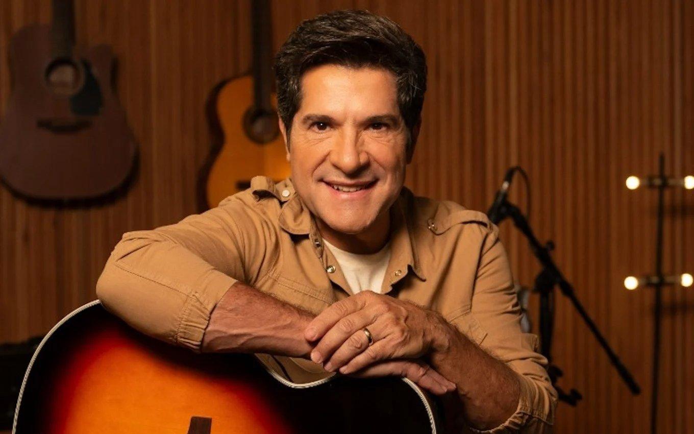 Imagem mostra o cantor Daniel sorridente, segurando um violão em um ambiente de estúdio, promovendo o programa Viver Sertanejo, da TV Globo, do qual é apresentador.