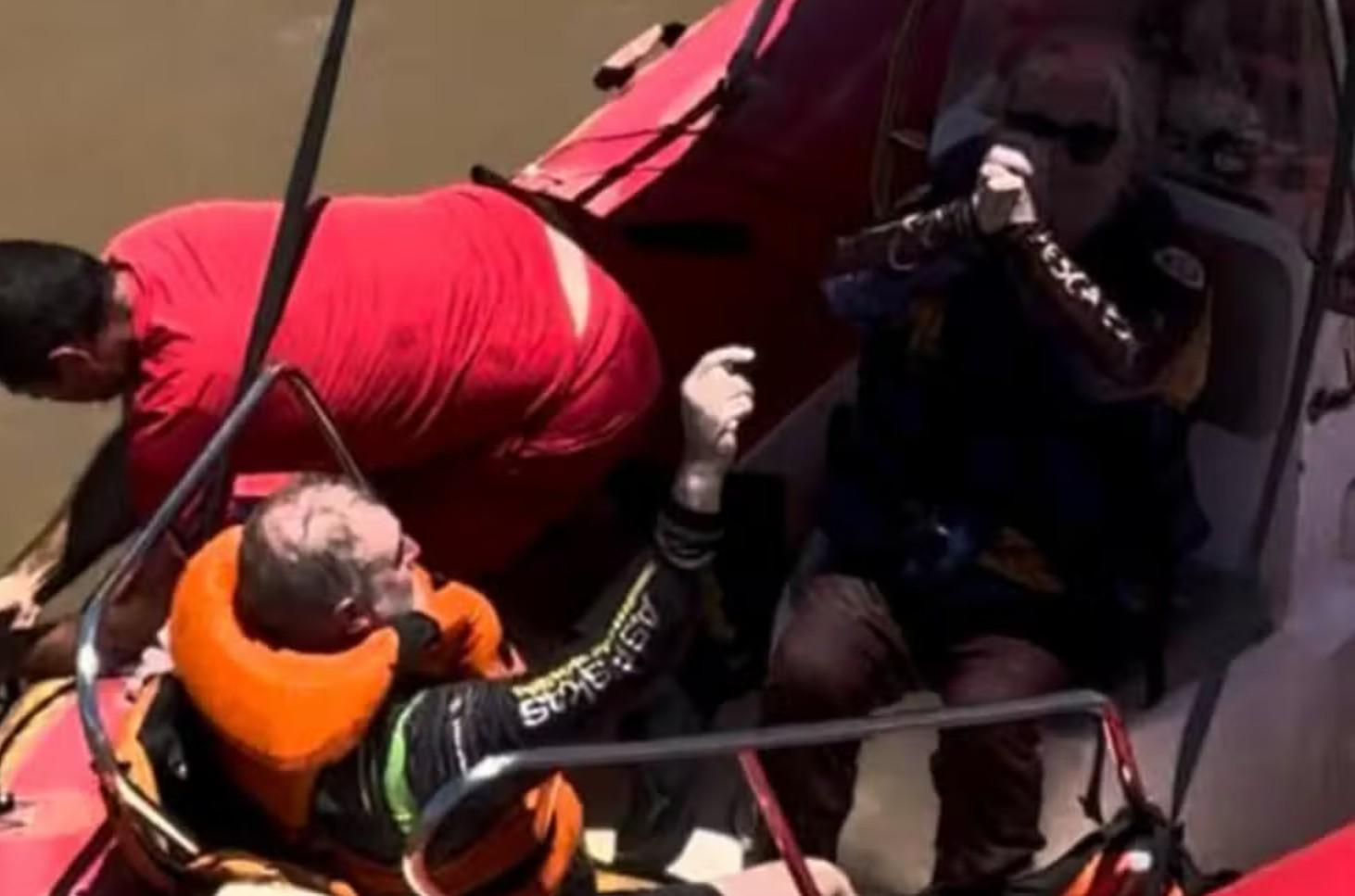 Pessoas sendo resgatadas com boias laranjas e embarcação dentro do Rio Paraná.
