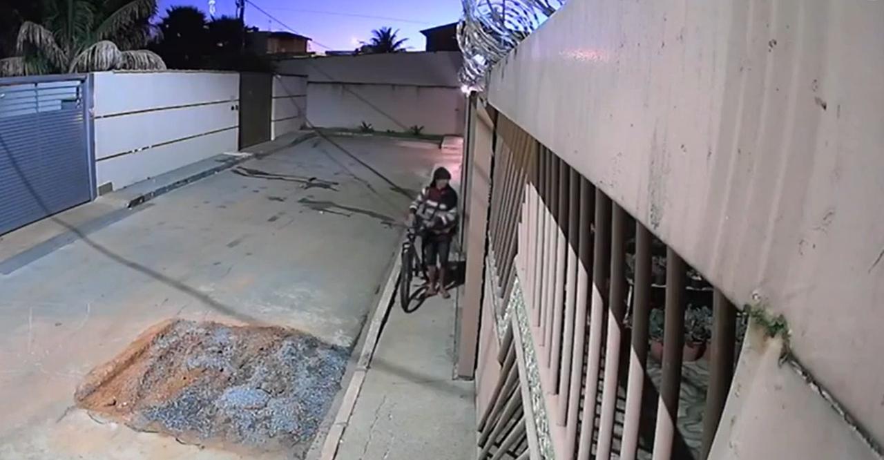 Homem em uma bicicleta sai de um portão de uma casa.