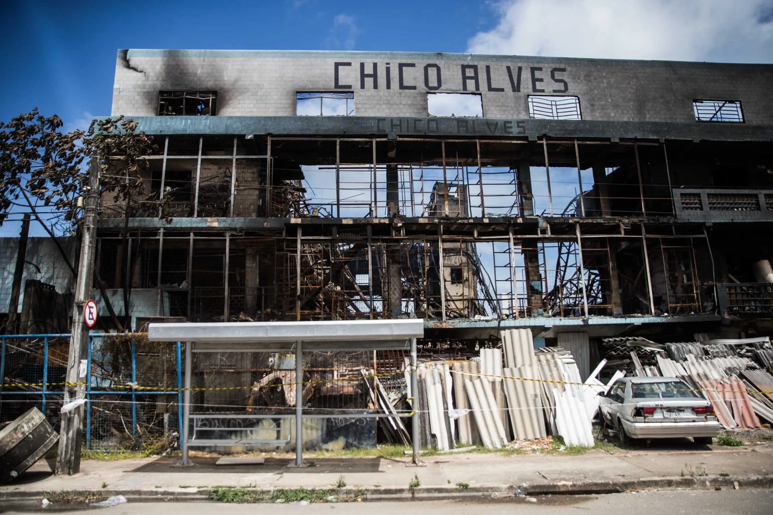 Fachada da sucata Chico Alves incendiada, com ruínas e restos de materiais.