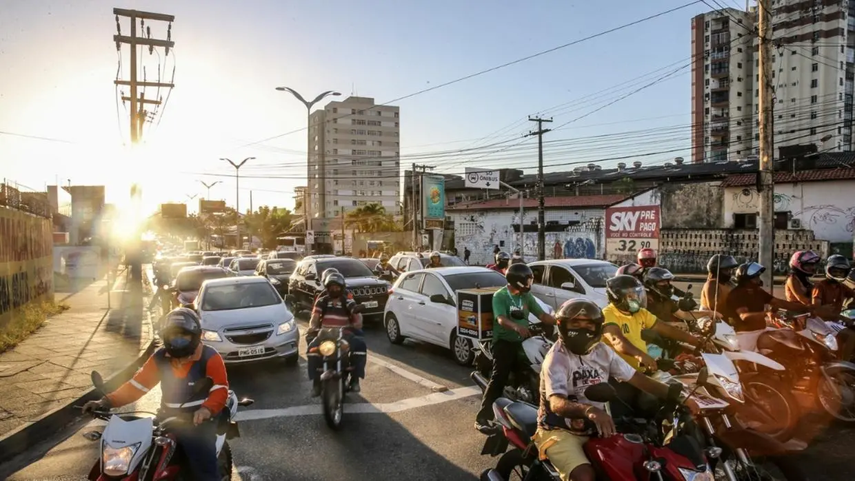 Motociclistas parados em semáforo em avenida de Fortaleza.