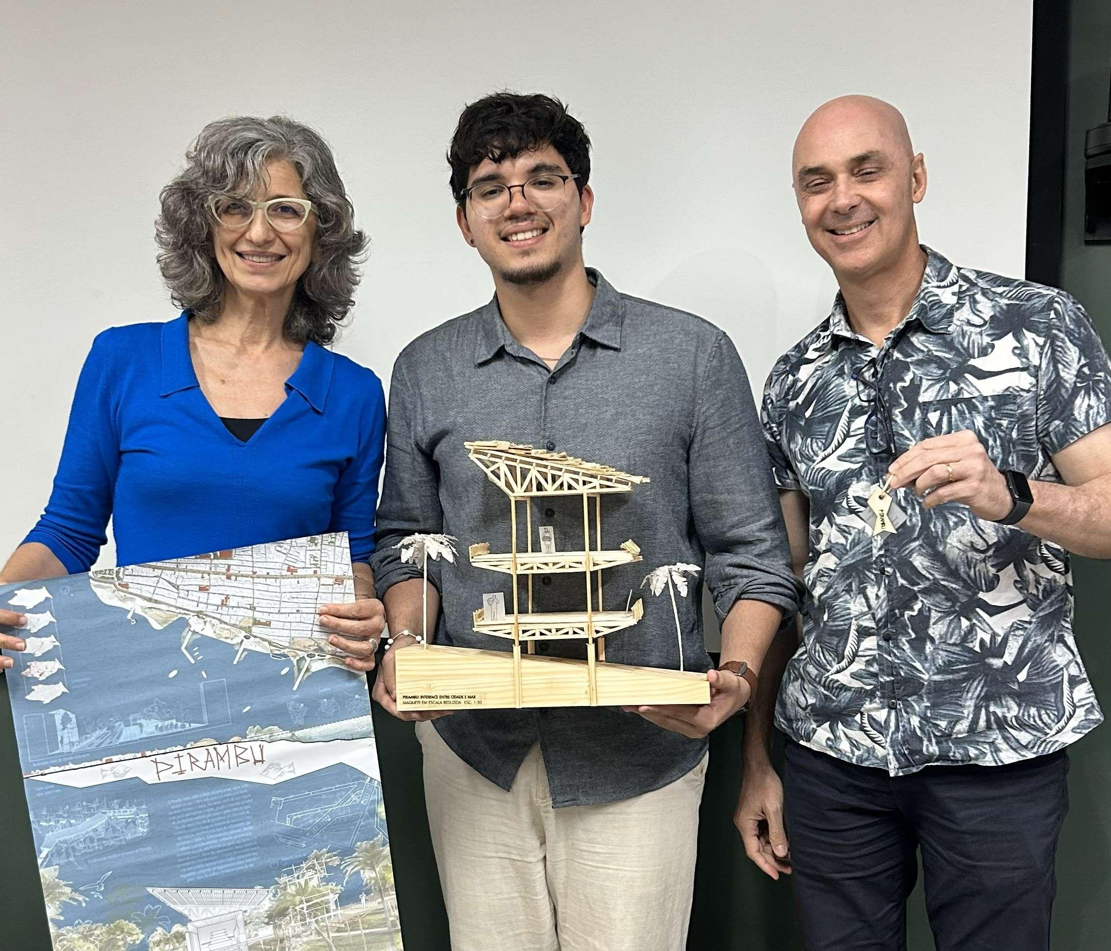 Grupo de pessoas segurando maquete e prêmio, celebrando o projeto de engenharia ou arquitetura, em ambiente interno