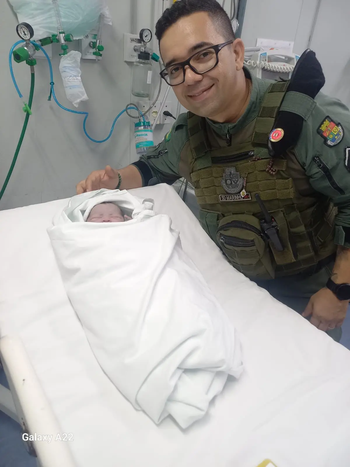policial militar ao lado do bebe que ele ajudou no parto.