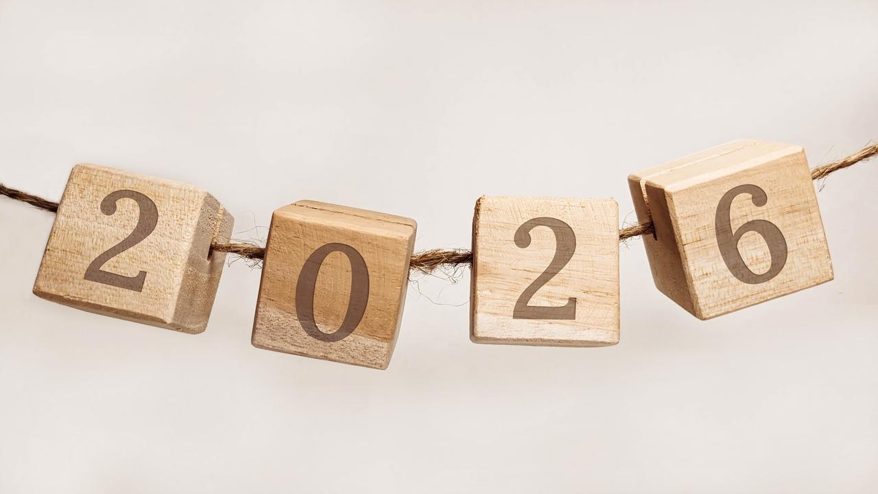 Quatro cubos de madeira clara estão pendurados em um varal de corda rústica, exibindo individualmente os números que formam o ano 