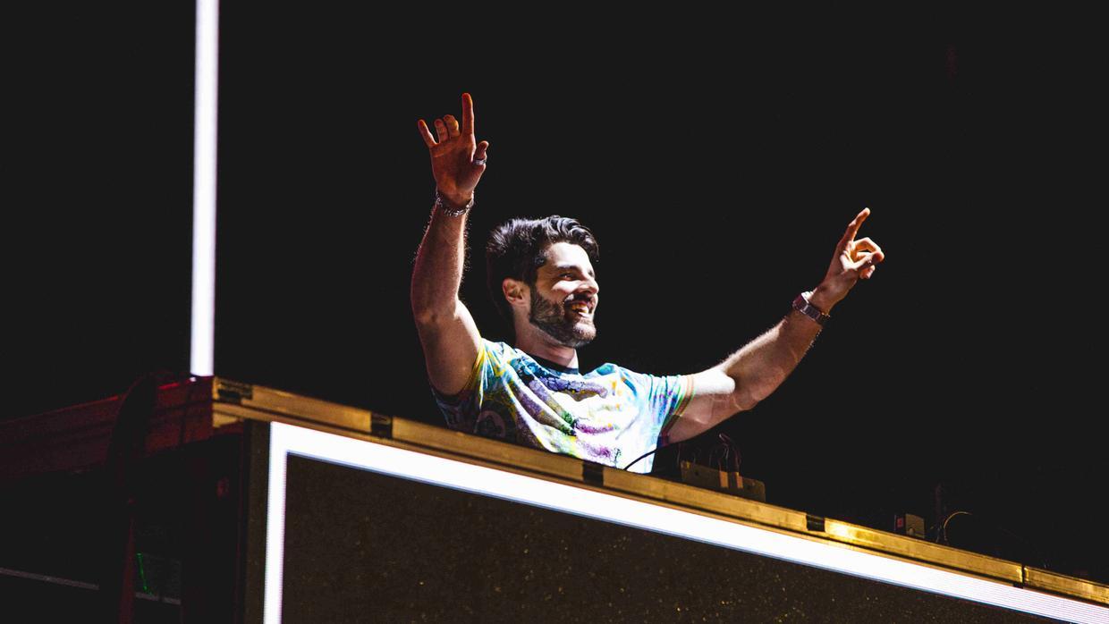 Alok com braços levantados, atrás de pick up de som.