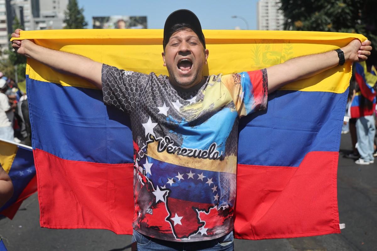 Venezuelano nas ruas do Chile com bandeira da Venezuela comemorando captura de Nicolás Maduro pelos EUA.
