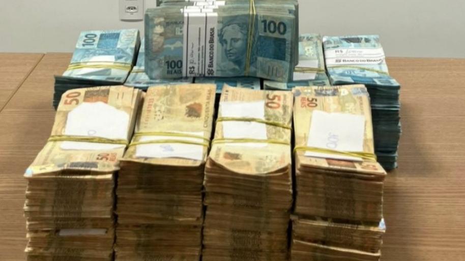 A foto mostra quatro pilhas de R$ 40 e, atrás, outras pilhas de R$ 100, que totalizam R$ 400 mil, em cima de uma mesa de madeira.