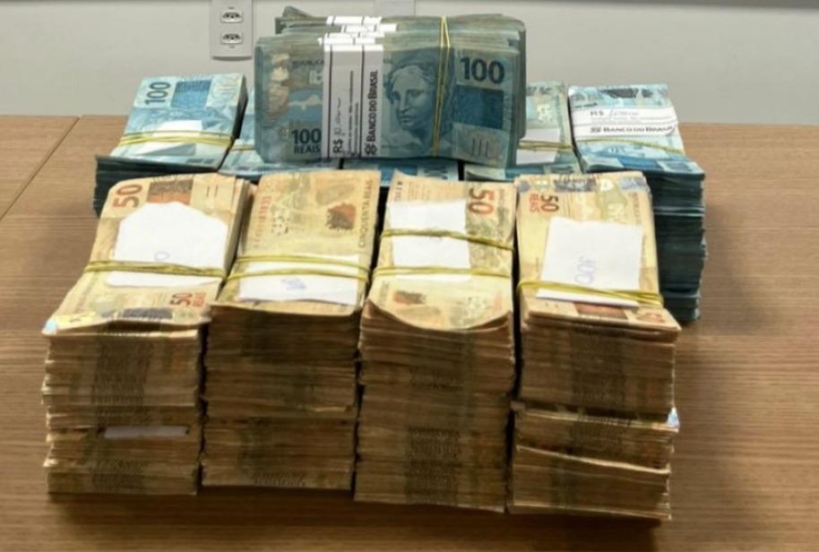 A foto mostra quatro pilhas de R$ 40 e, atrás, outras pilhas de R$ 100, que totalizam R$ 400 mil, em cima de uma mesa de madeira.