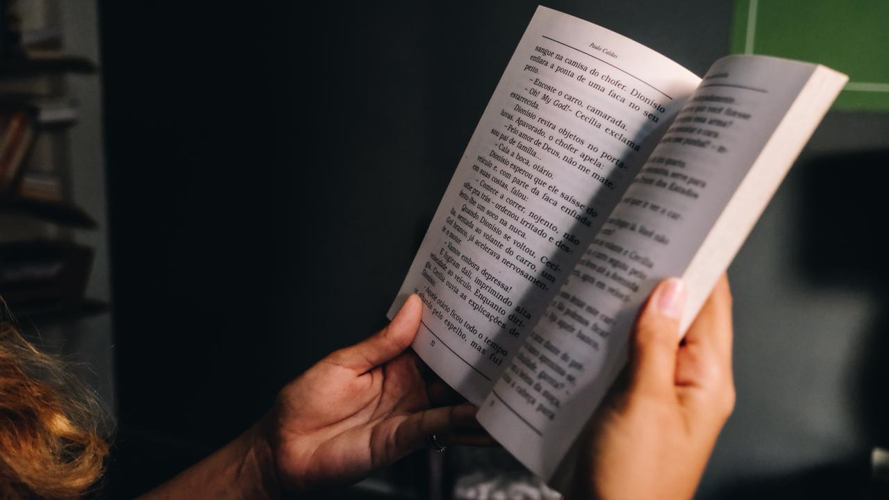 Mulher segurando um livro sob meia luz.
