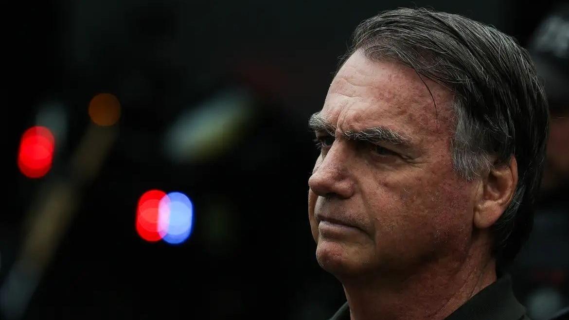 Bolsonaro de perfil, sério. É um homem idoso de cabelo grisalho penteado para o lado.