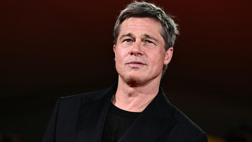 foto do ator Brad Pitt com terno e blusa preta.