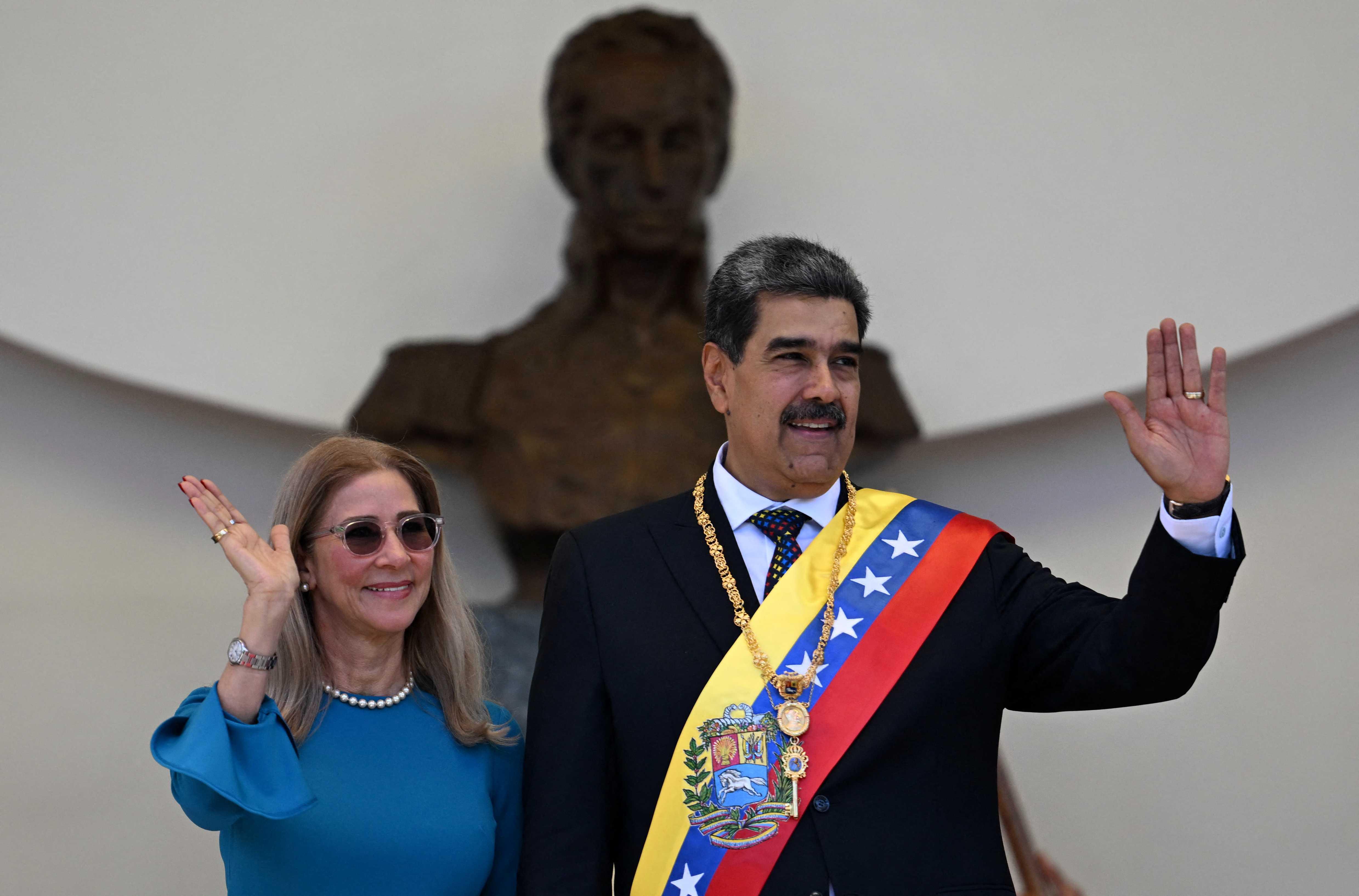 O presidente da Venezuela, Nicolas Maduro, e sua esposa Cilia Flores acenam para os apoiadores enquanto deixam o Capitolio -sede da Assembleia Nacional- após prestarem o juramento durante a inauguração presidencial em Caracas no dia 10 de janeiro de 2025.