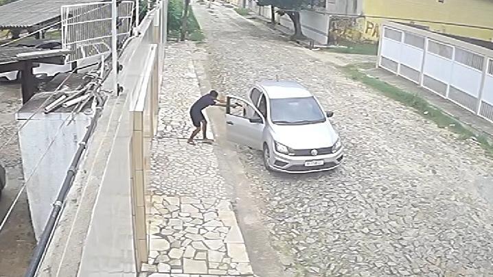 A foto mostra um homem armado, com roupa escura, atirando contra ocupantes de um carro Volkswagen, de cor prata, em uma rua, no Ceará.
