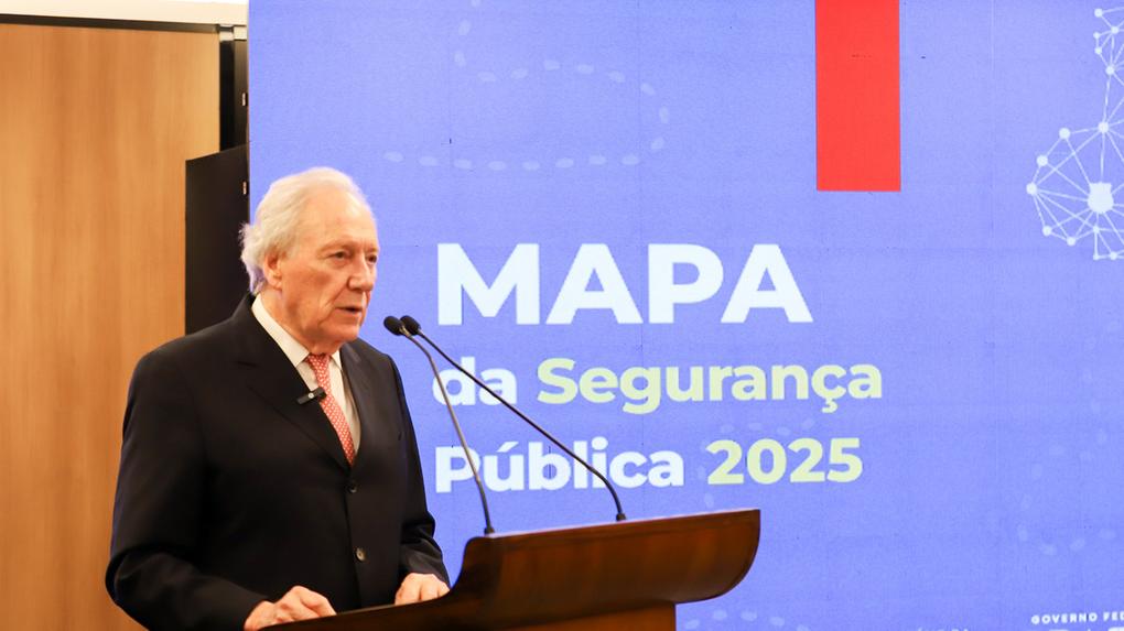 Autoridade em traje formal discursa em um púlpito com dois microfones durante evento institucional. Ao fundo, um grande painel azul exibe o texto “MAPA da Segurança Pública 2025”, com referências ao Ministério da Justiça e Segurança Pública e ao Governo Federal do Brasil, indicando uma cerimônia oficial voltada ao tema da segurança pública.