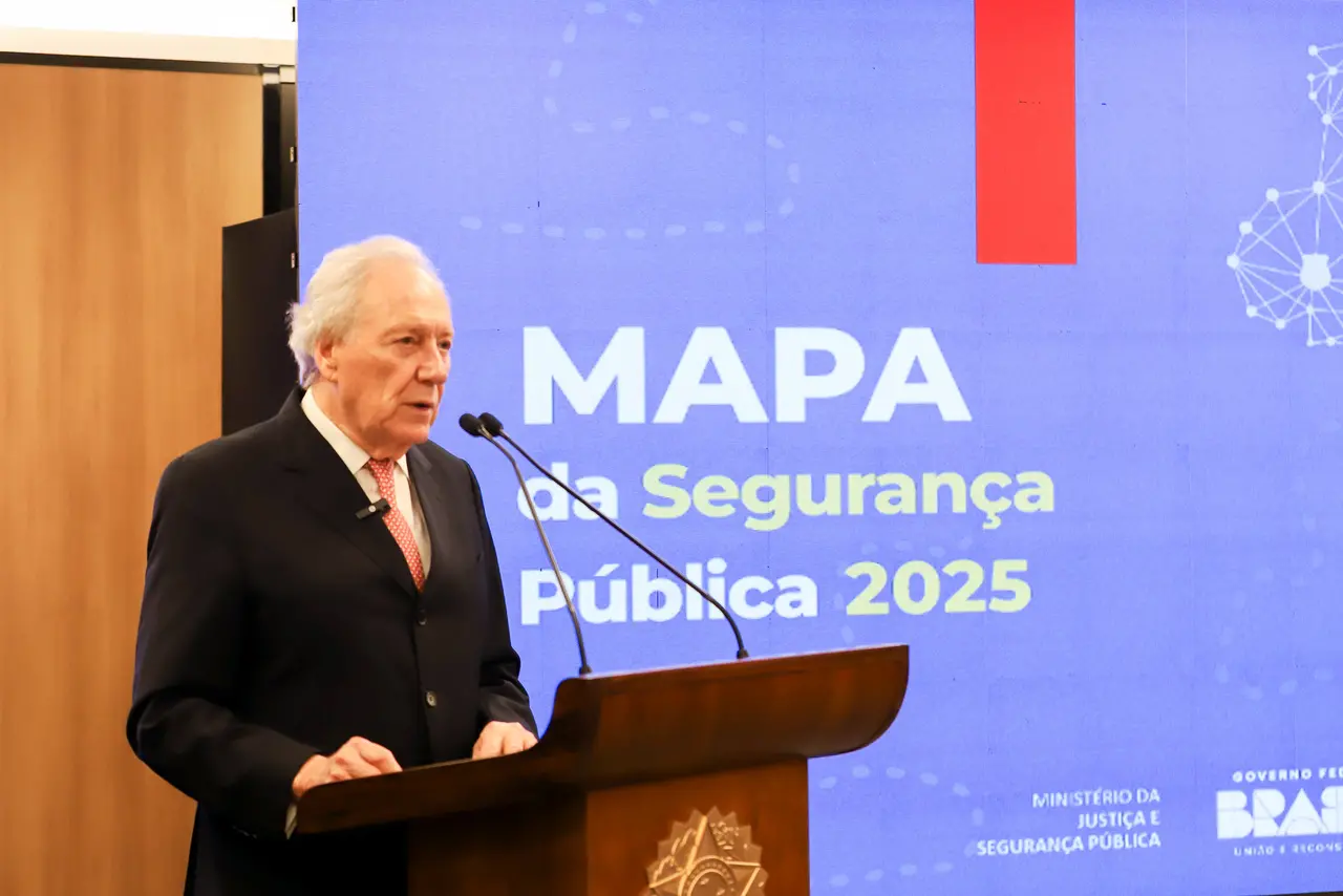 Autoridade em traje formal discursa em um púlpito com dois microfones durante evento institucional. Ao fundo, um grande painel azul exibe o texto “MAPA da Segurança Pública 2025”, com referências ao Ministério da Justiça e Segurança Pública e ao Governo Federal do Brasil, indicando uma cerimônia oficial voltada ao tema da segurança pública.