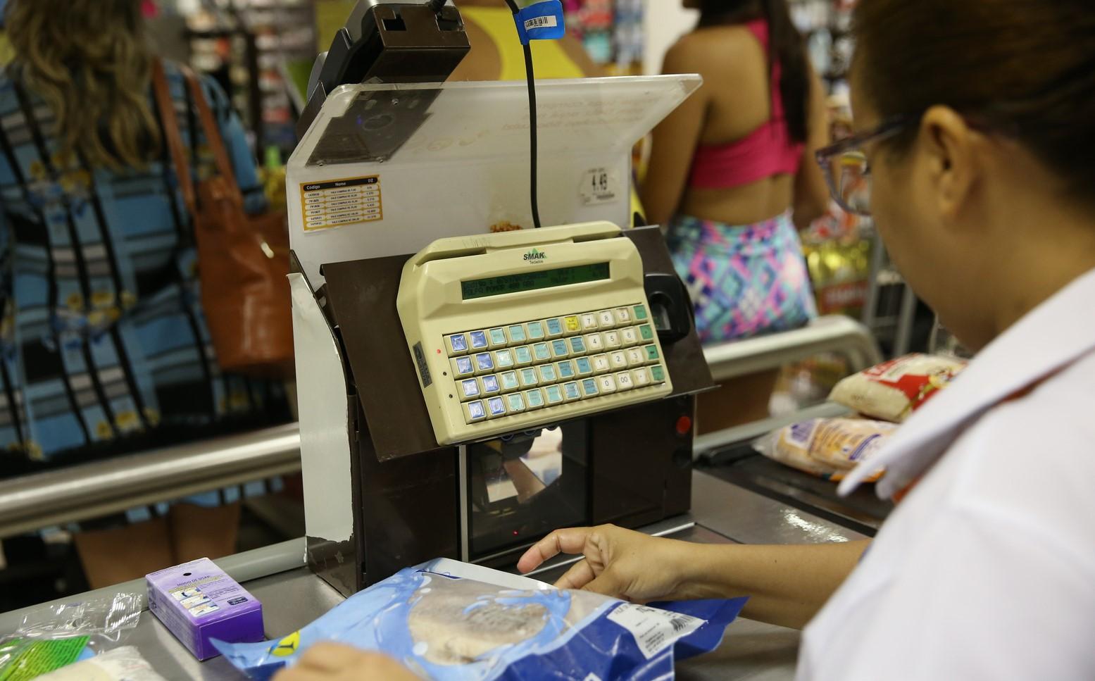 Foto de atendente de pequeno supermercado no Ceará finalizando compra.