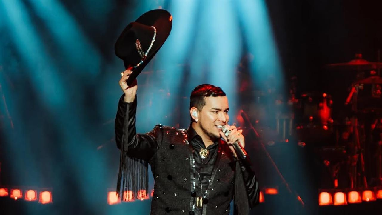 Yeison Jiménez em show com microfone na mão e chapéu para o alto na outra mão.