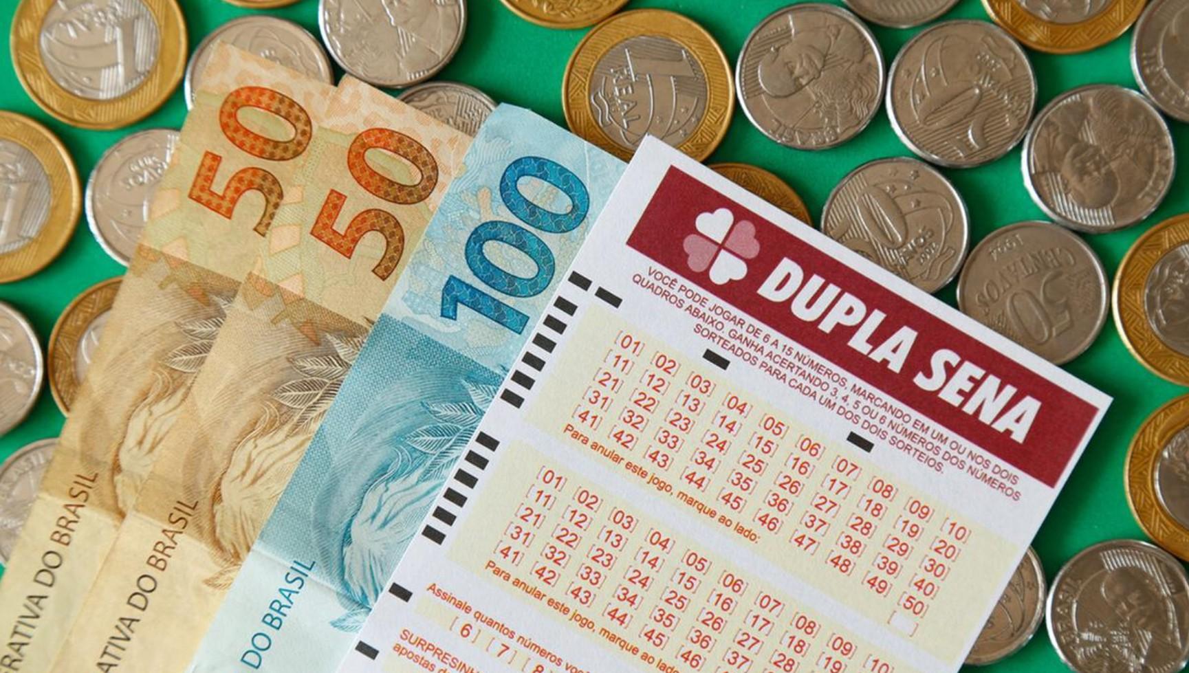 Volantes do sorteio da Dupla-Sena, da Caixa Econômica Federal, em cima de uma mesa branca.