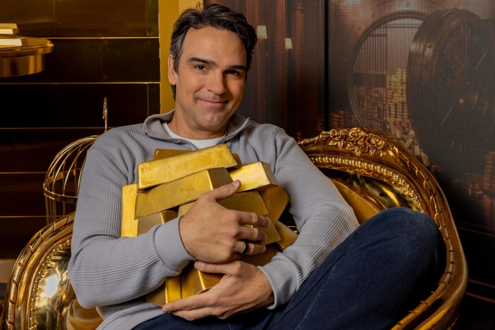 Tadeu Schmidt segura barras de ouro.