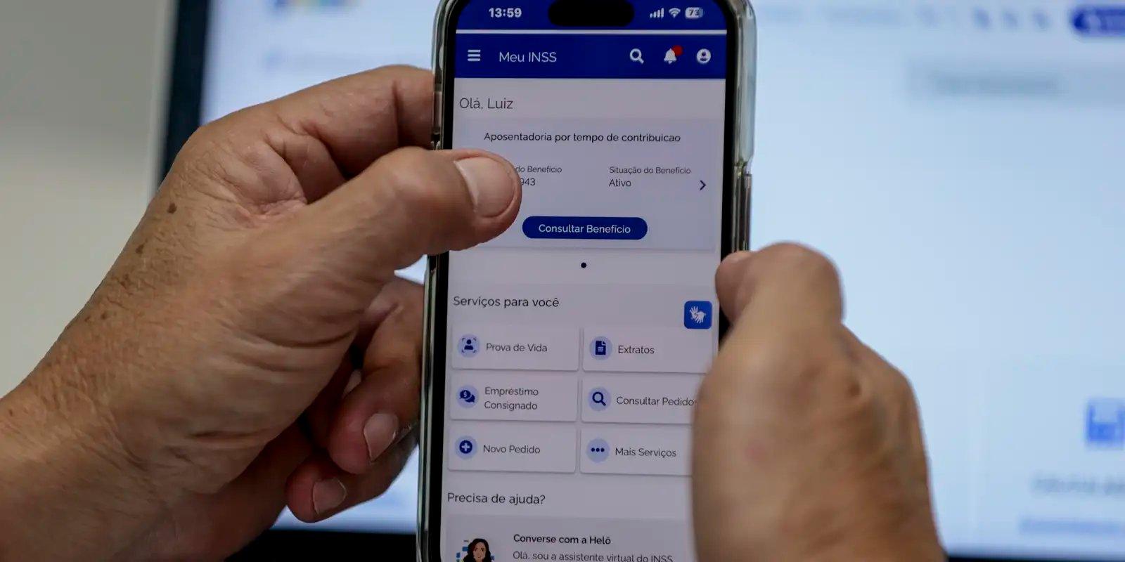 Mãos de uma pessoa utilizando o aplicativo Meu INSS em um smartphone para consultar serviços previdenciários. Imagem usada em matéria sobre prova de vida.